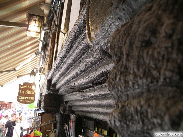 photo de poutre de bois travaillée surmontant la vitrine d'un magasin
