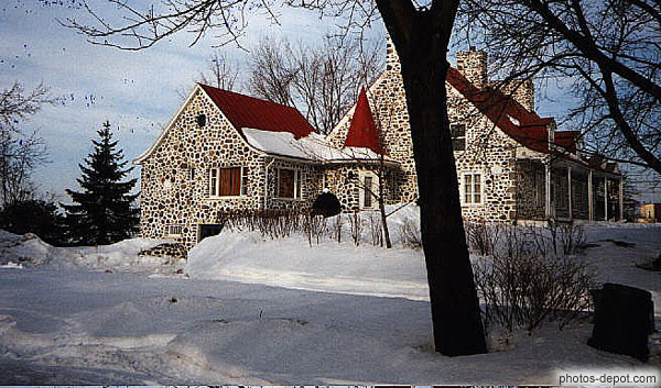 photo de maison de pierres au toit rouge dans la neige