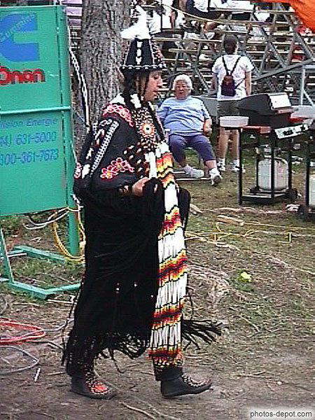 Indenne en costume noir, écharpe bariolée et chapeau en cone