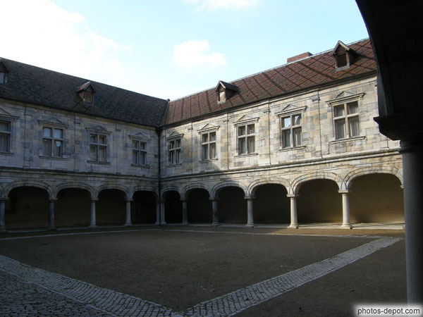 photo de belle facade renaissance, de pierres de taille grises et arches entourant large cour intérieure