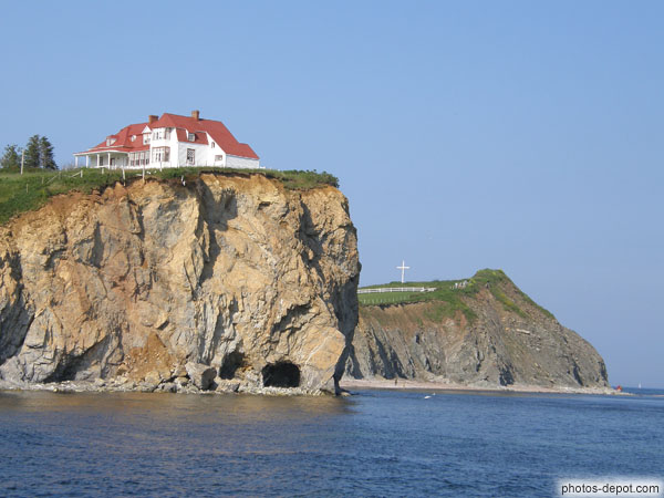 photo de maison au toit rouge et croix blanche sur rocher