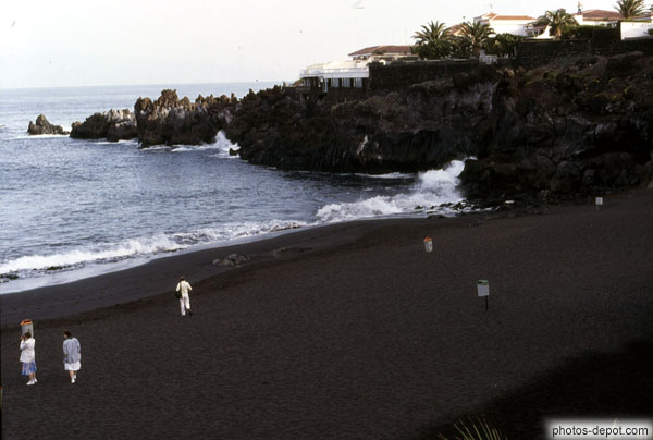 Gens sur la plage et rochers avançant dans la mer