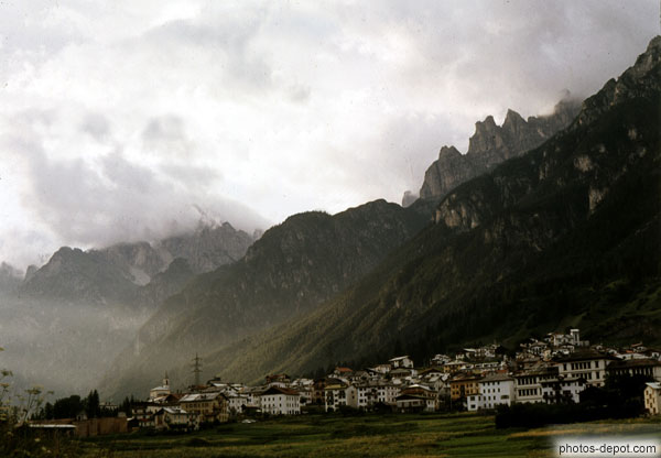 photo de village encaissé sous les montagnes menaçantes