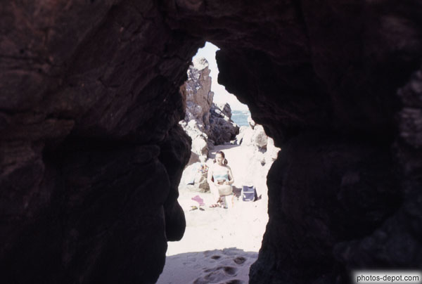 photo de femme bronzant sur la plage vu à travers une fente dans le rocher