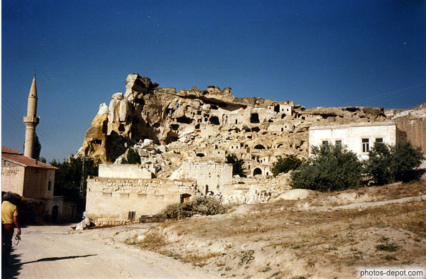 photo de rocher troglodytique devant village au minaret