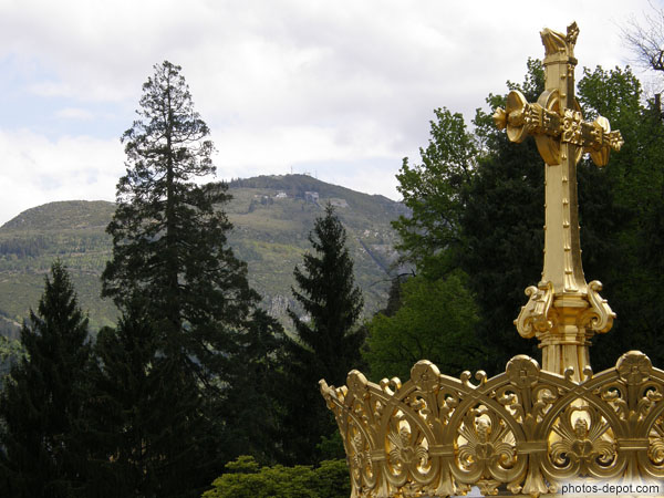 photo de croix dorée et couronne à la Vierge devant la colline
