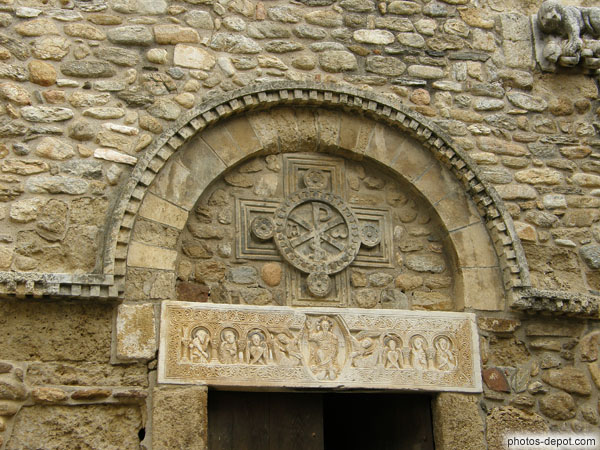 photo de Linteau en marbre blanc au-dessus du portail du XI° siècle, pièce majeure de l'art roman. Représente un Christ bénissant, entouré d'anges,  séraphins à six ailes et 4 apôtres dans un cadre de colonnettes et arcatures, surmonté d'une croix de St André