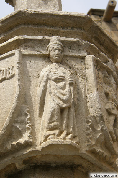 photo de femme entre blasons sculpté la Creu, croix des chemins médiévale
