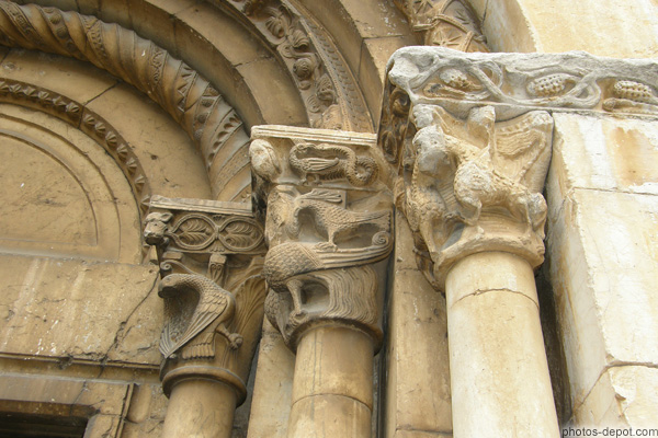 photo de trois chapiteaux ornés d'animaux sur portail de l'église médiévale