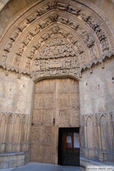 photo de portail de gauche, porte de bois sculpté aux scènes de la passion surmonté de scènes bibliques