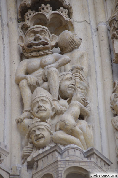photo de diable couronné et grassouillet écrasant trois damnés : un riche, un évêque et un roi au bas des voussures de droite du portail du Jugement dernier