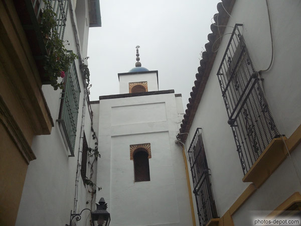 photo de clocher blanc au fond d'une rue