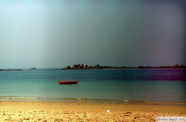 photo de barque rouge face à la plage