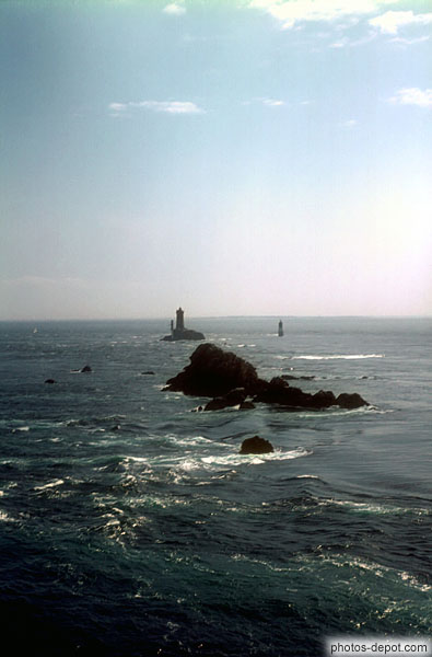 photo de rochers et phare dépassant sortant de la mer