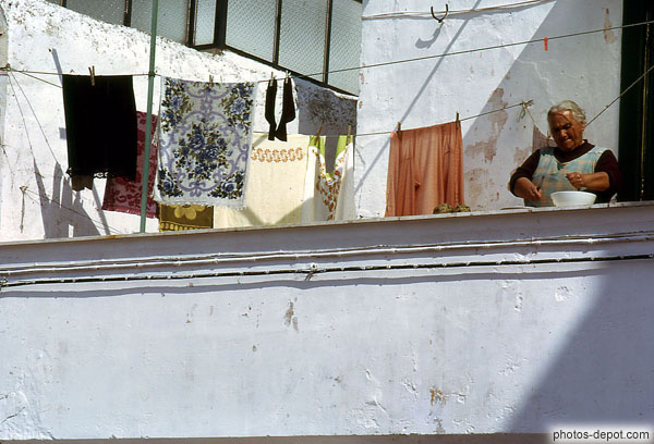 photo de linge qui sèche à la terrasse et femme épluchant les légumes