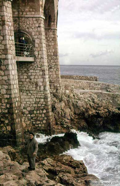 photo d'homme sur les rochers, murailles devant la mer