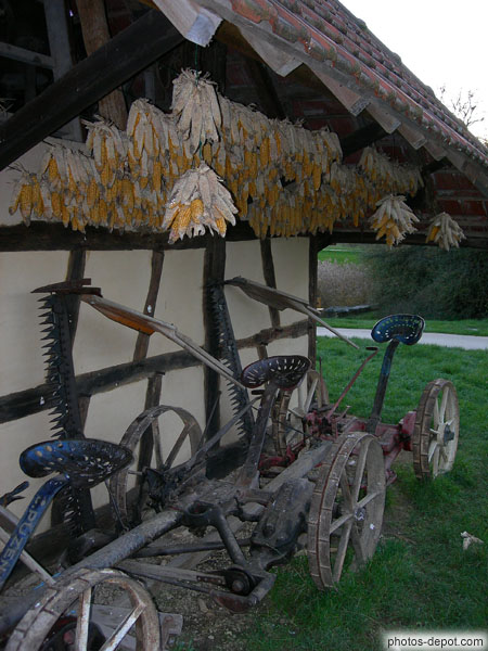 photo de Panouilles de maïs suspendues sous l'auvent et faux mécaniques