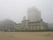 Dans le brouillard, donjon fortifié, chatelet surmonté de la cloche de l'horloge